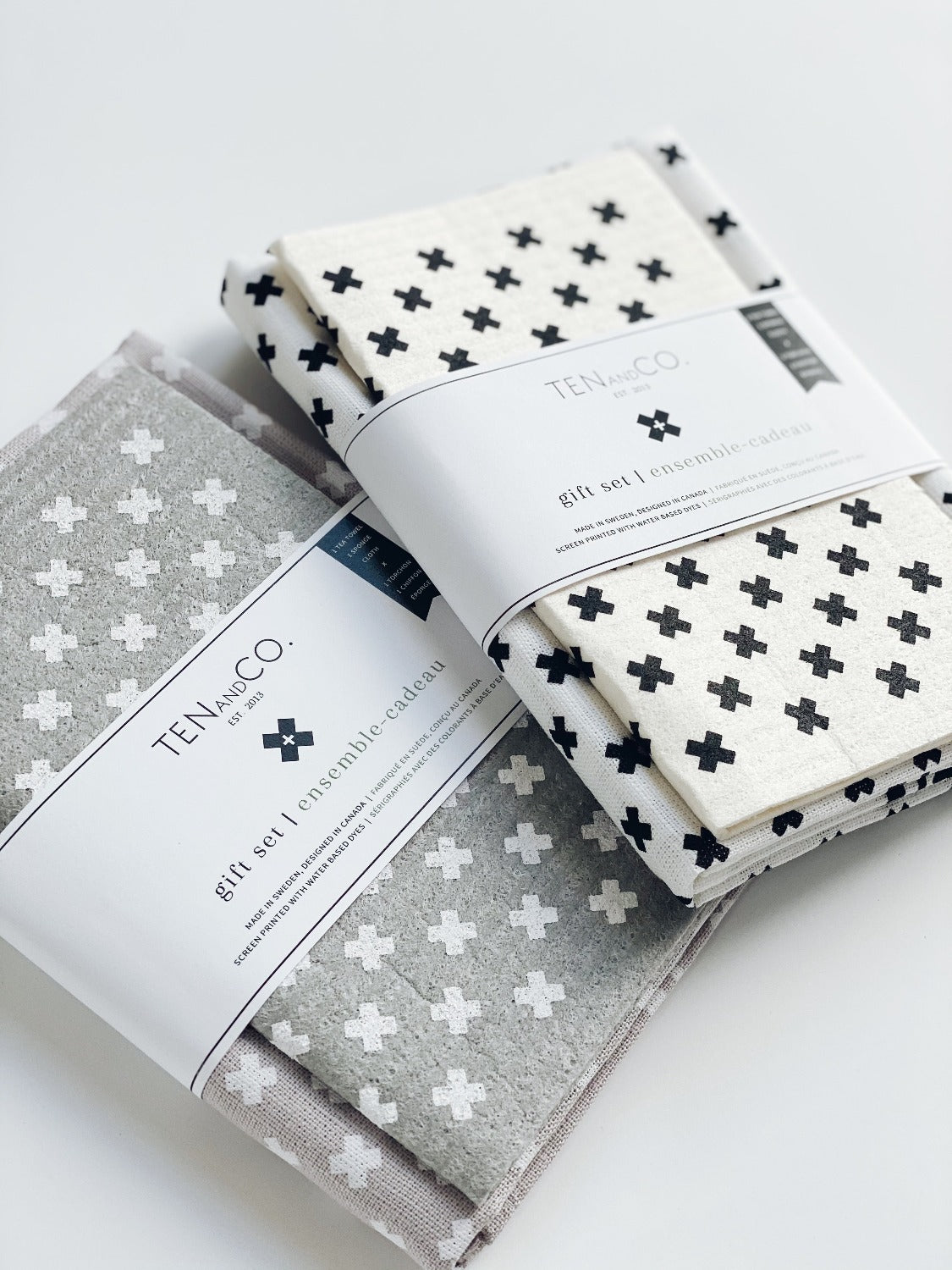 Product image of Tiny X White on Warm Grey gift set on a white background. In this image there are two gift sets with belly bands. The one on the left is Tiny X White on Warm Grey and the one on the right is Tiny X Black on white.